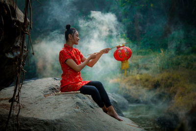 Side view of woman holding red umbrella