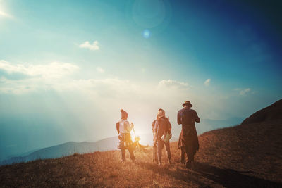 Hikers on field against blue sky