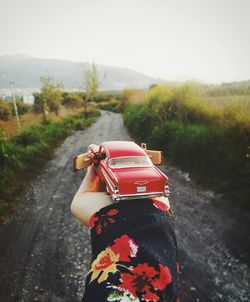 Cropped hand holding toy car over road