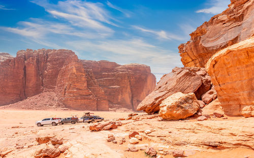 Red stones and rocks of wadi rum desert with cars in the background, jordan