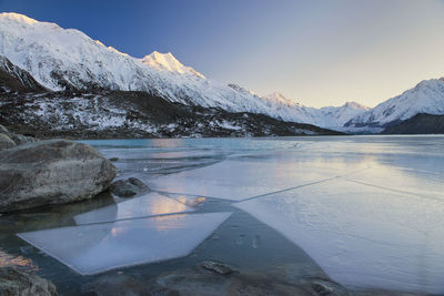 Scenic view of frozen lake by mountains against sky