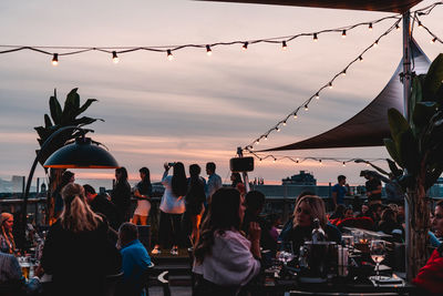 People at restaurant against sky during sunset