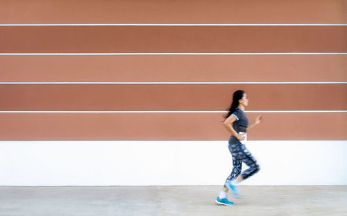 Side view of woman running by wall