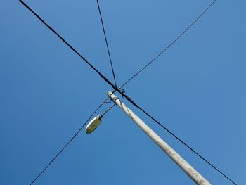 Low angle view of electricity pylon against clear blue sky