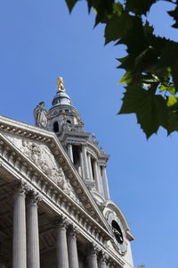 West front of st paul's cathedral as clear background and green leaves as blur foreground , london