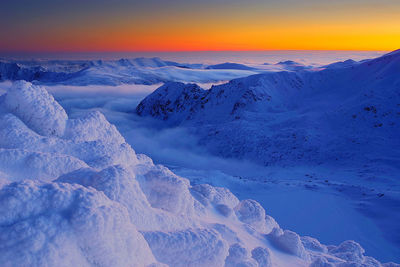 Scenic view of snow covered mountains against sky during sunset