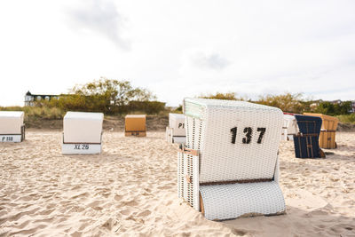 Hooded chairs on beach against sky