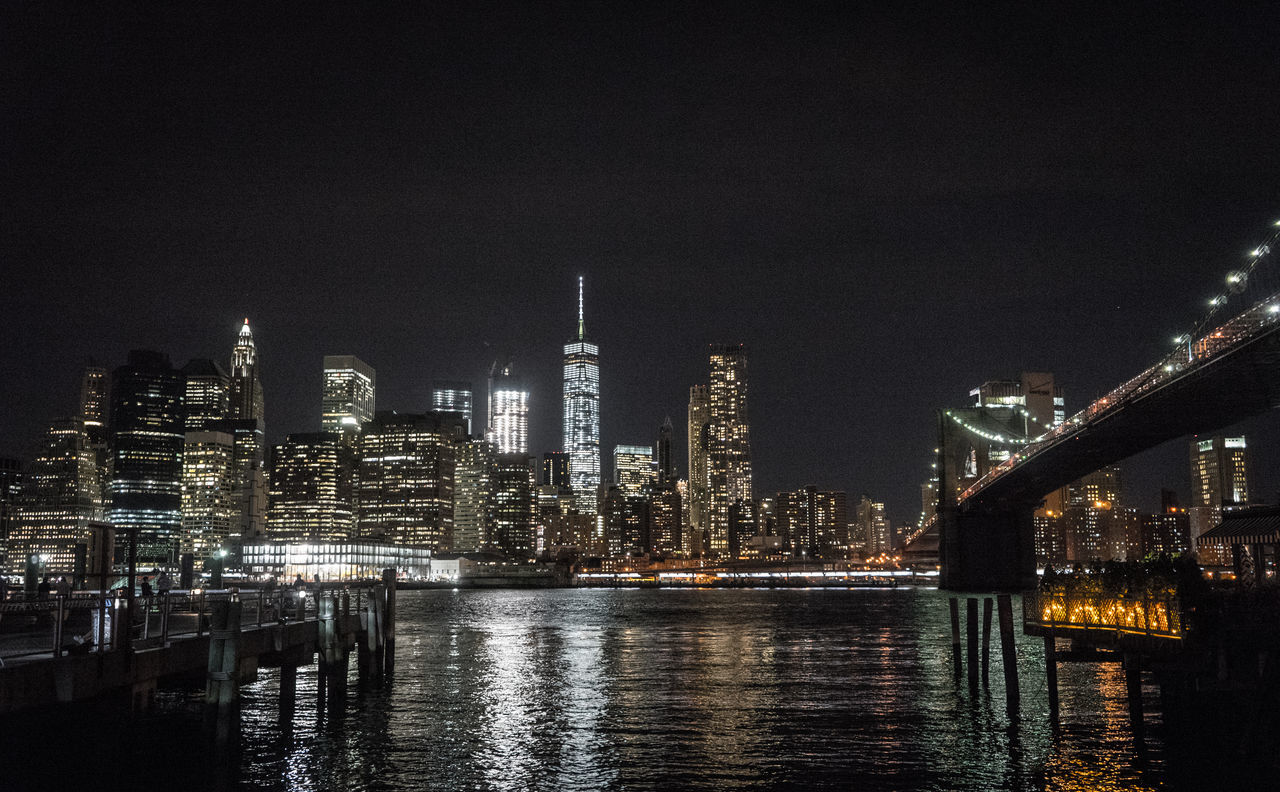 ILLUMINATED CITY BY RIVER AGAINST SKY