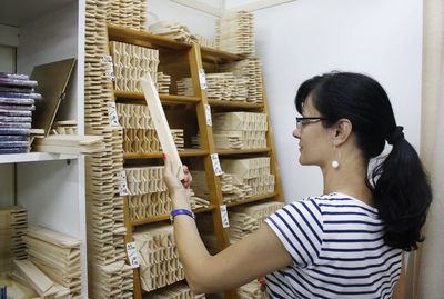 Woman choosing wooden equipment while standing at store