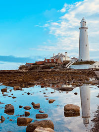 Lighthouse by sea against sky