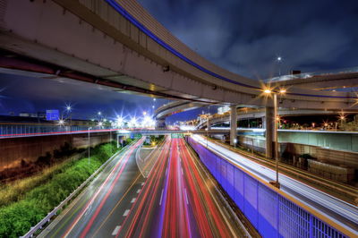 Light trails on bridge in city against sky at night