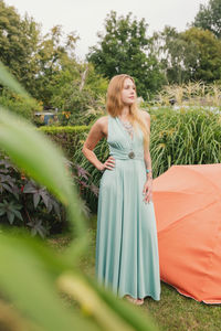 Young woman looking away while standing against plants