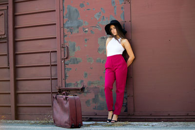 Portrait of woman standing against door