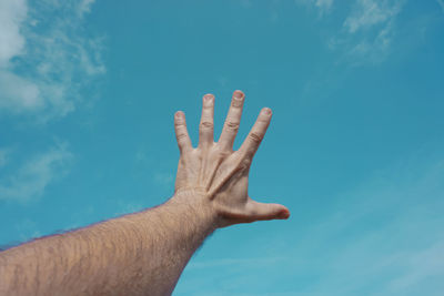 Cropped hand gesturing against sky