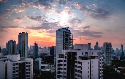 Modern buildings in city against sky during sunset