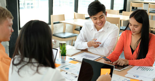 Colleagues discussing at desk in office