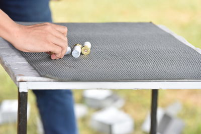 Midsection of woman holding bullets on table