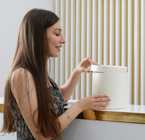 Side view of young woman standing against wall