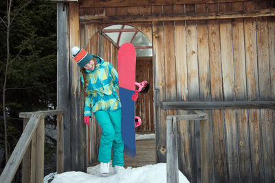 Woman carrying snowboard on steps during winter