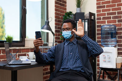 Businessman wearing mask talking on video call at office