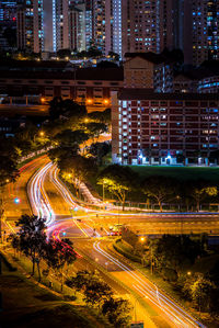 High angle view of light trails on city street by buildings