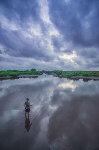 Man cycling on water against sky