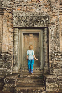 Rear view of woman standing at entrance of old temple