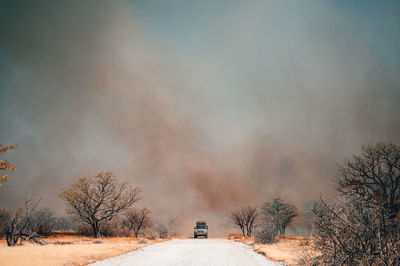 Car on dirt road against smoke