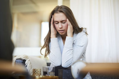 Stressed teenager with head in hands talking to therapist at workshop