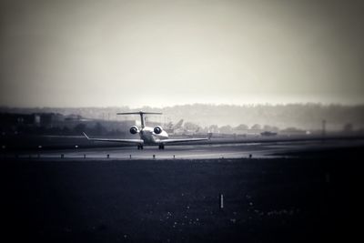 Airplane at airport runway against sky