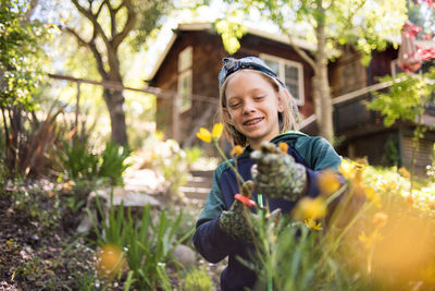 Happy boy cutting flowers while standing in garden