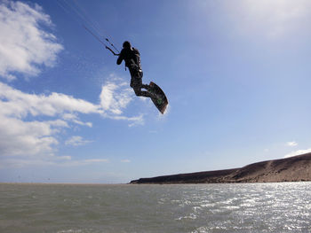 Low angle view of man jumping in sea against sky