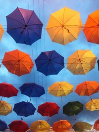 Low angle view of multi colored umbrellas against blue sky