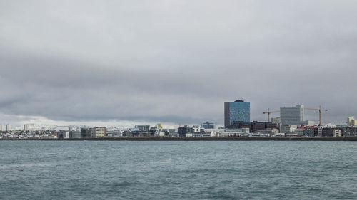 Sea by buildings against sky in city