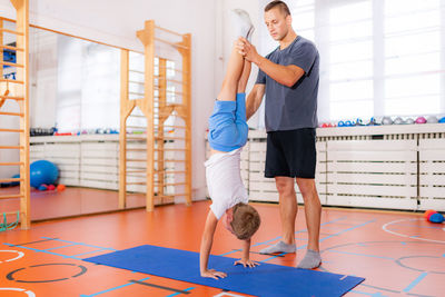 Physical activity for children, child doing a hand stand with trainer