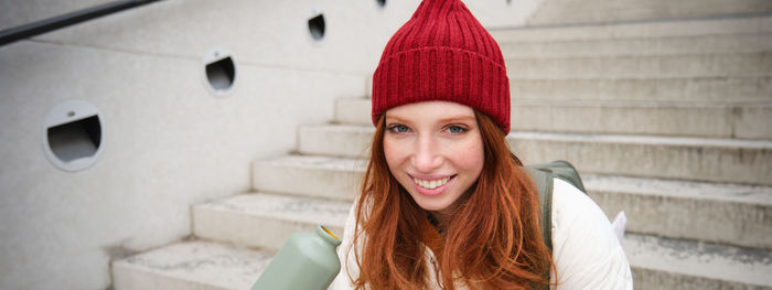 Portrait of young woman standing against wall