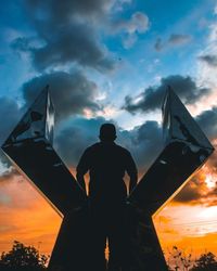 Rear view of silhouette man standing against sky during sunset