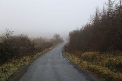 Road amidst bare trees against clear sky