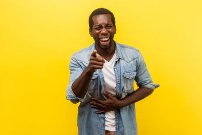 Portrait of smiling young man against yellow background