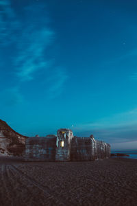 Built structure on beach against sky at night