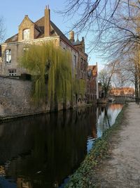 Canal by old building against sky