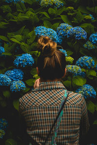 Rear view of woman with umbrella standing against plants