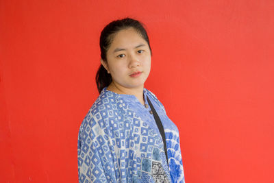 Portrait of young woman standing against yellow background