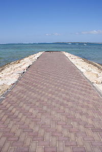 Footpath by sea against clear sky