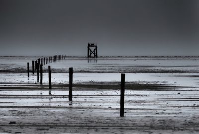 Wooden posts on beach against sky