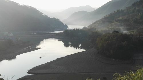 Scenic view of river by mountains against sky