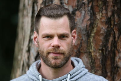 Portrait of smiling man against tree trunk