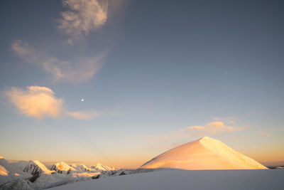 Scenic view of snowcapped mountains against sky during sunset