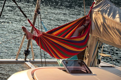 Man relaxing in the hammock set on the sail boat anchored in the sea