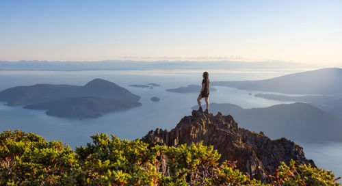 Man standing on rock against sky